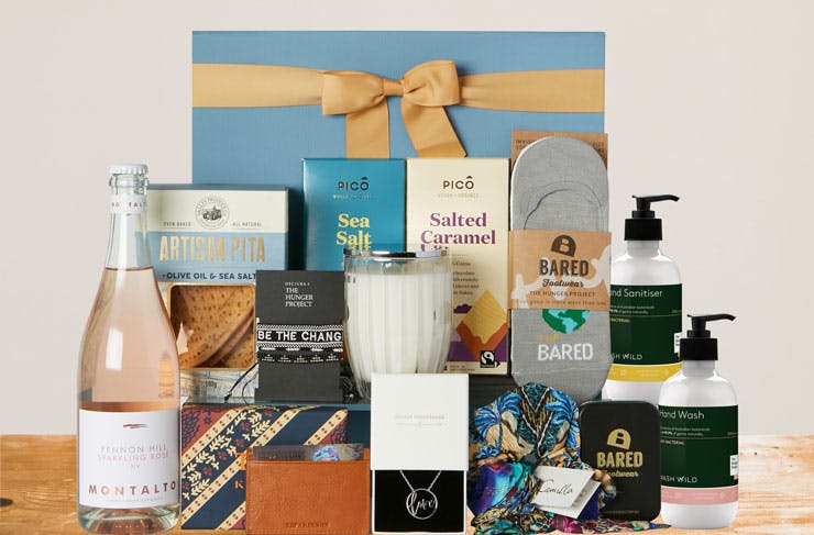 A collage of items included in The Hunger Project hamper, including rose wine, hand soap, candles, and chocolate. 
