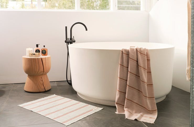 A round-shaped bath draped with a rust-coloured towel