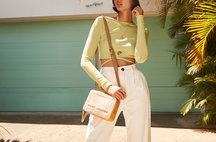 A model wearing The Iconic owned brands in front of a green garage door. 