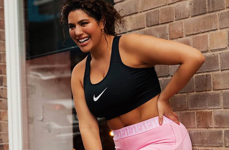 A Woman wearing a black Nike crop and pink Nike shorts. 