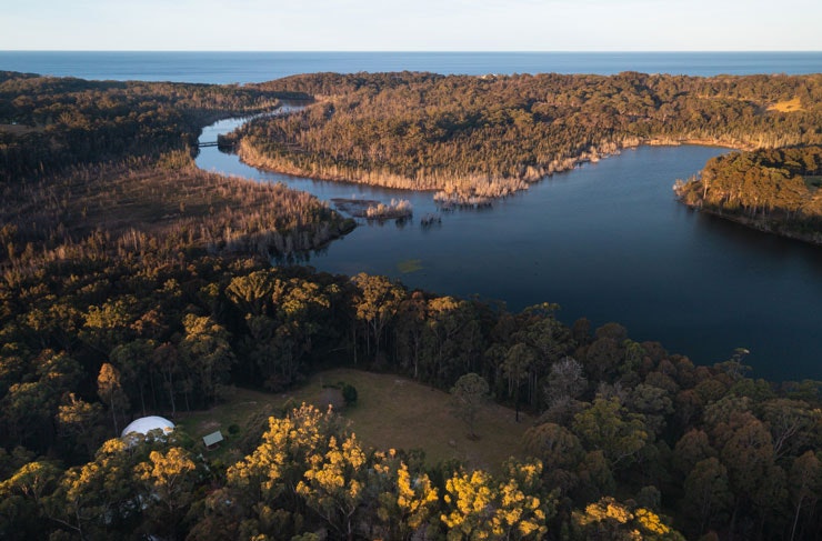 A river winding in from the ocean, surrounded by natural bushland. 