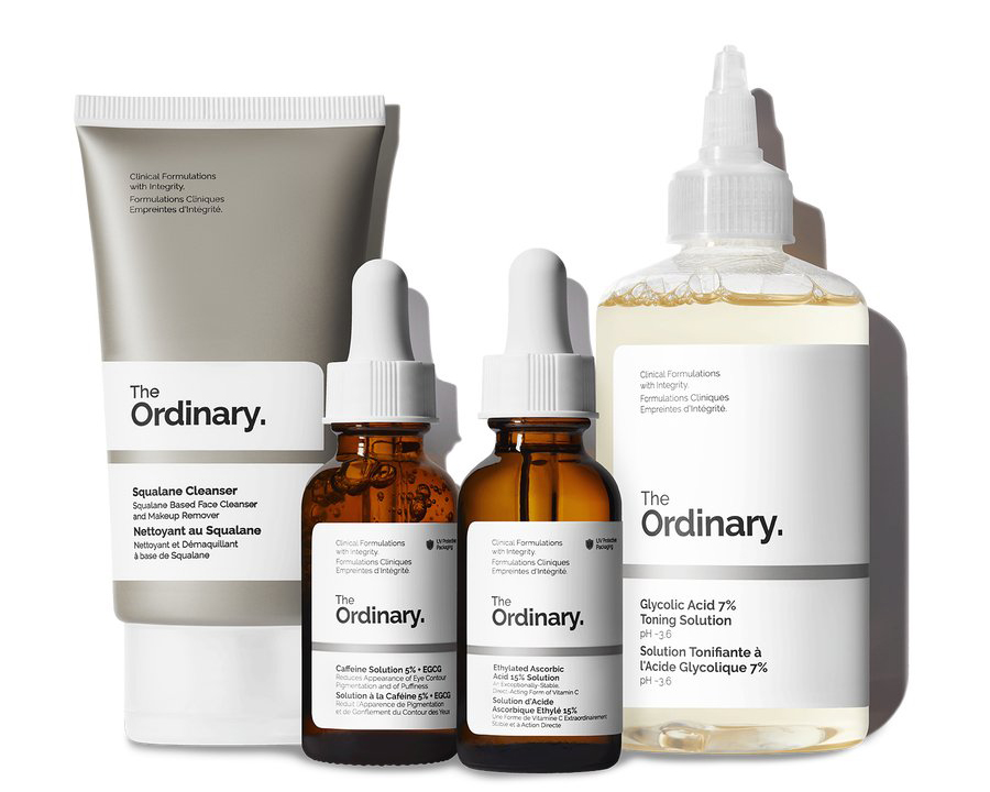 Quatre articles de The Ordinary Skincare sur fond blanc - un tube argenté de nettoyant au squalane, deux flacons compte-gouttes en verre brun de solution de caféine à 5 % + EGCG et solution d'acide ascorbique éthylé à 15 %, et une bouteille en plastique de solution tonifiante à 7 % d'acide glycolique