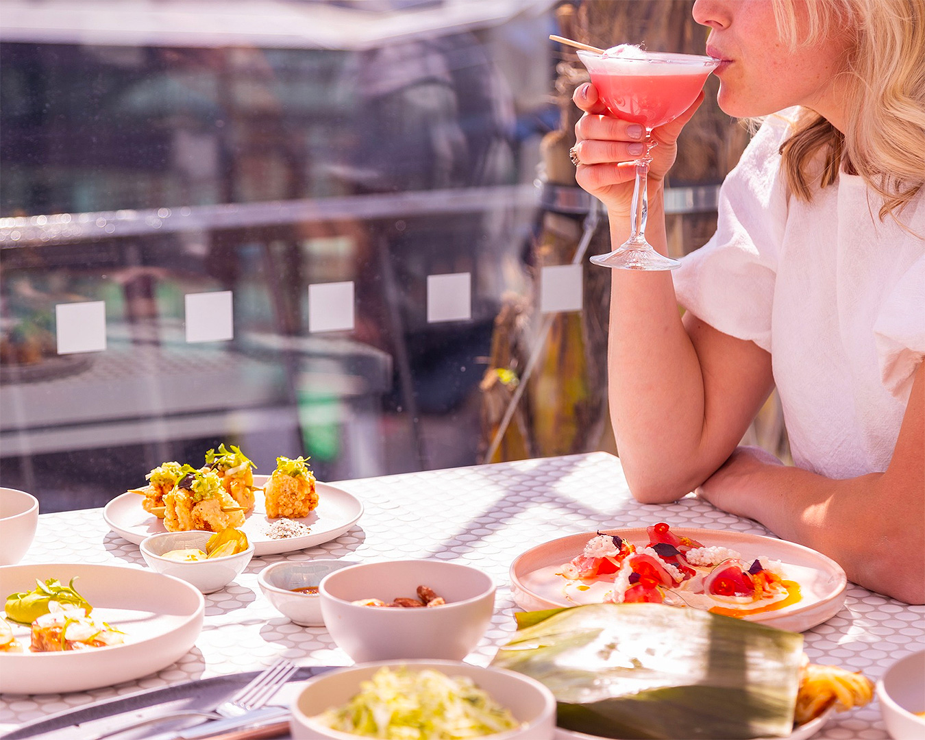 A woman sips on a cocktail at Pink Lady Rooftop, one of the best bars in Christchurch.