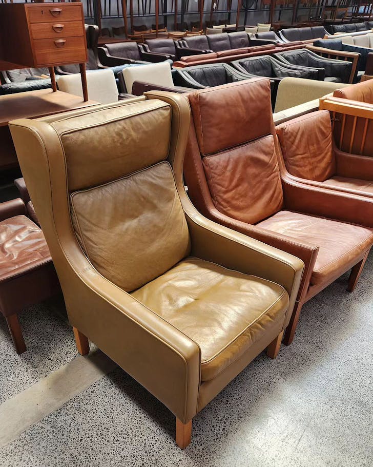 Second-hand wing back leather chairs with sofas in the background at The Vintage Shop.