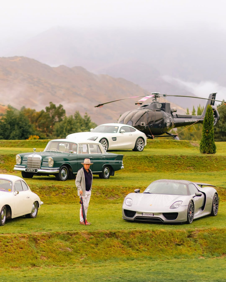 Exotic cars, a helicopter and a man with an umbrella, just contemplating it all.