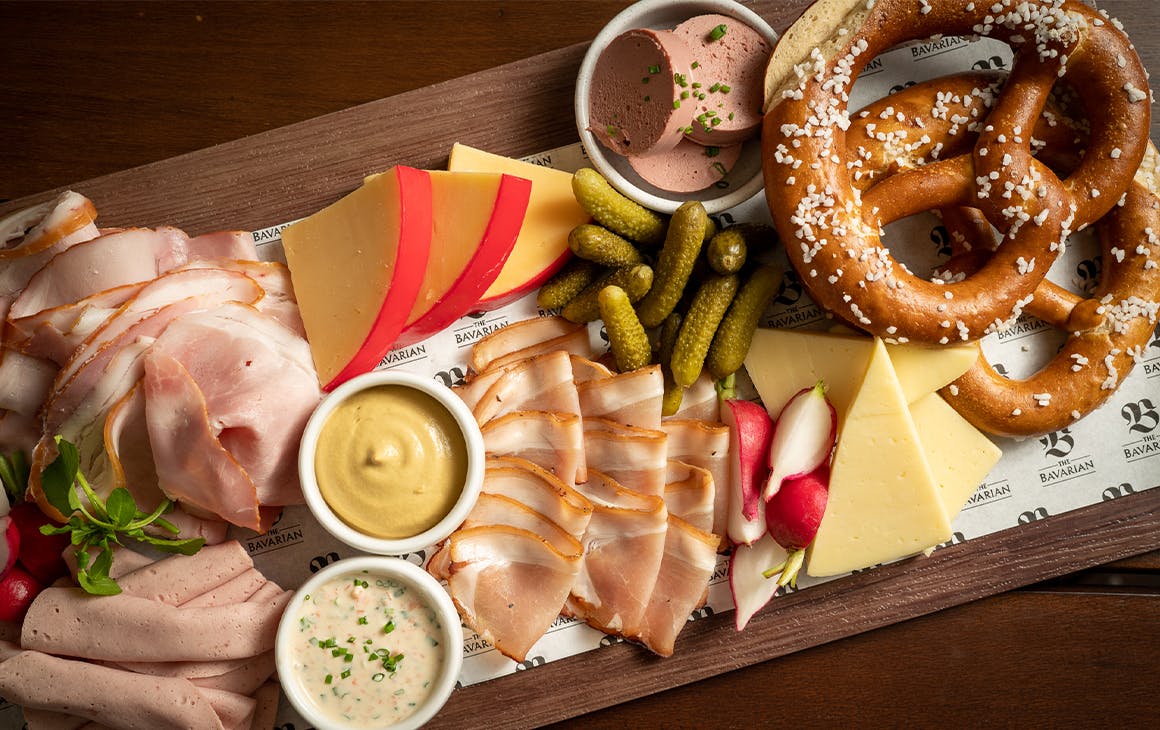 a board piled with various cold meat slices, cheese and pretzels