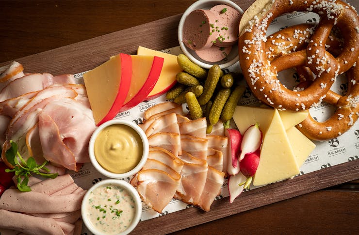 a board piled with various cold meat slices, cheese and pretzels