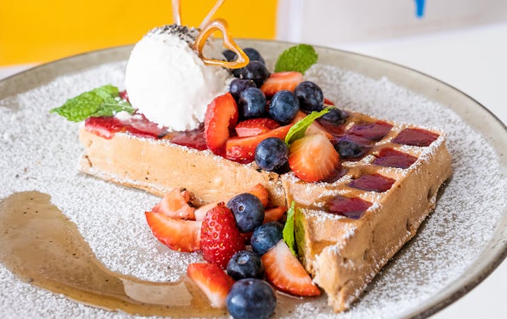 A waffle topped with ice cream and raspberry sauce