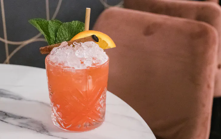 a peach coloured cocktail filled with ice