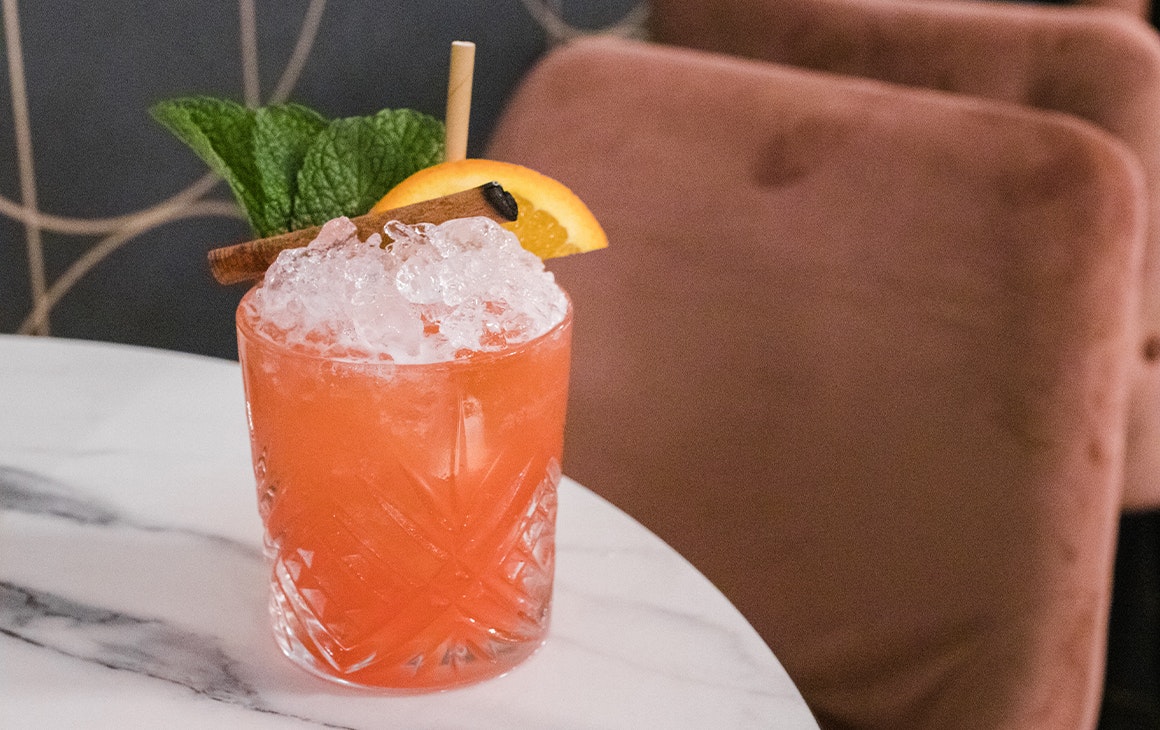 a peach coloured cocktail filled with ice
