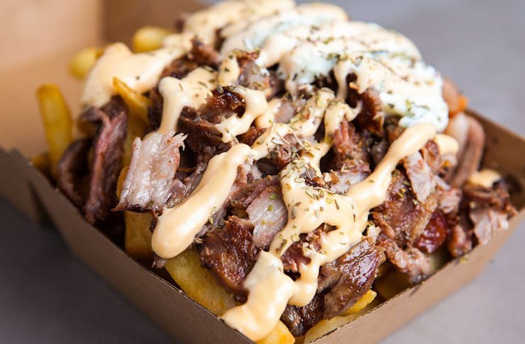 A box of fries topped with slow cooked meat and sauce 