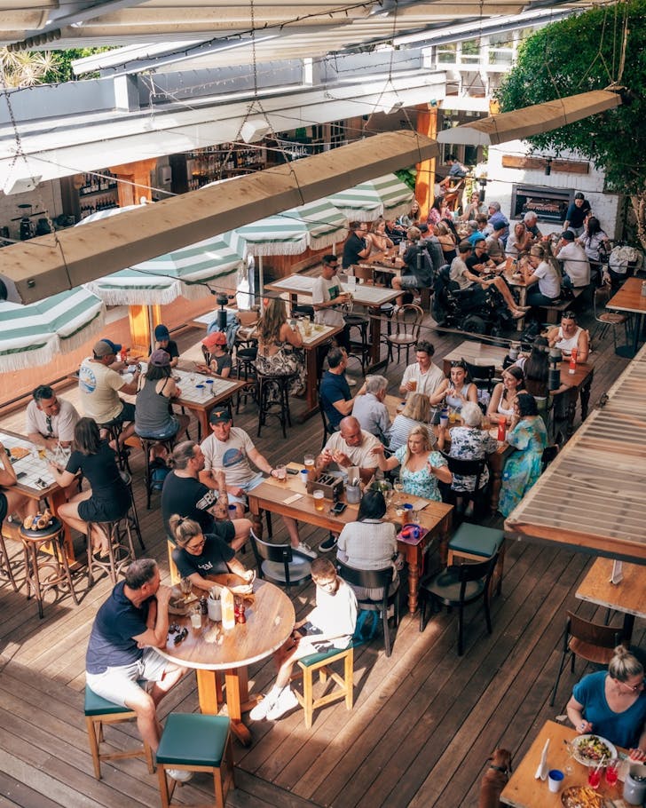 The Mona outdoor courtyard tables filled with groups eating and drinking