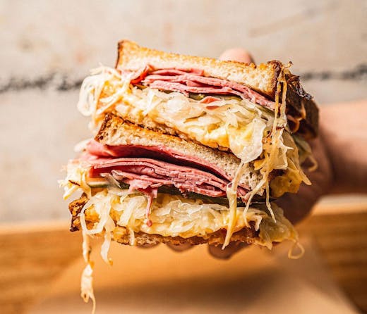 A reuben sandwich sliced in half from Theo's Deli. 