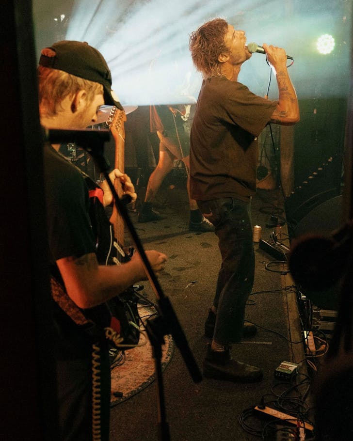 A man sings into a microphone on stage at The Rails in Byron Bay