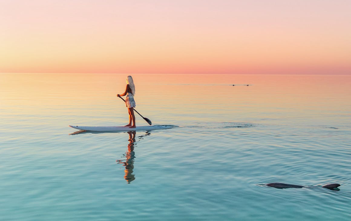 A stand up paddle boarder at sunset in Coral Bay