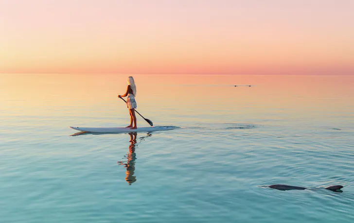 A stand up paddle boarder at sunset in Coral Bay