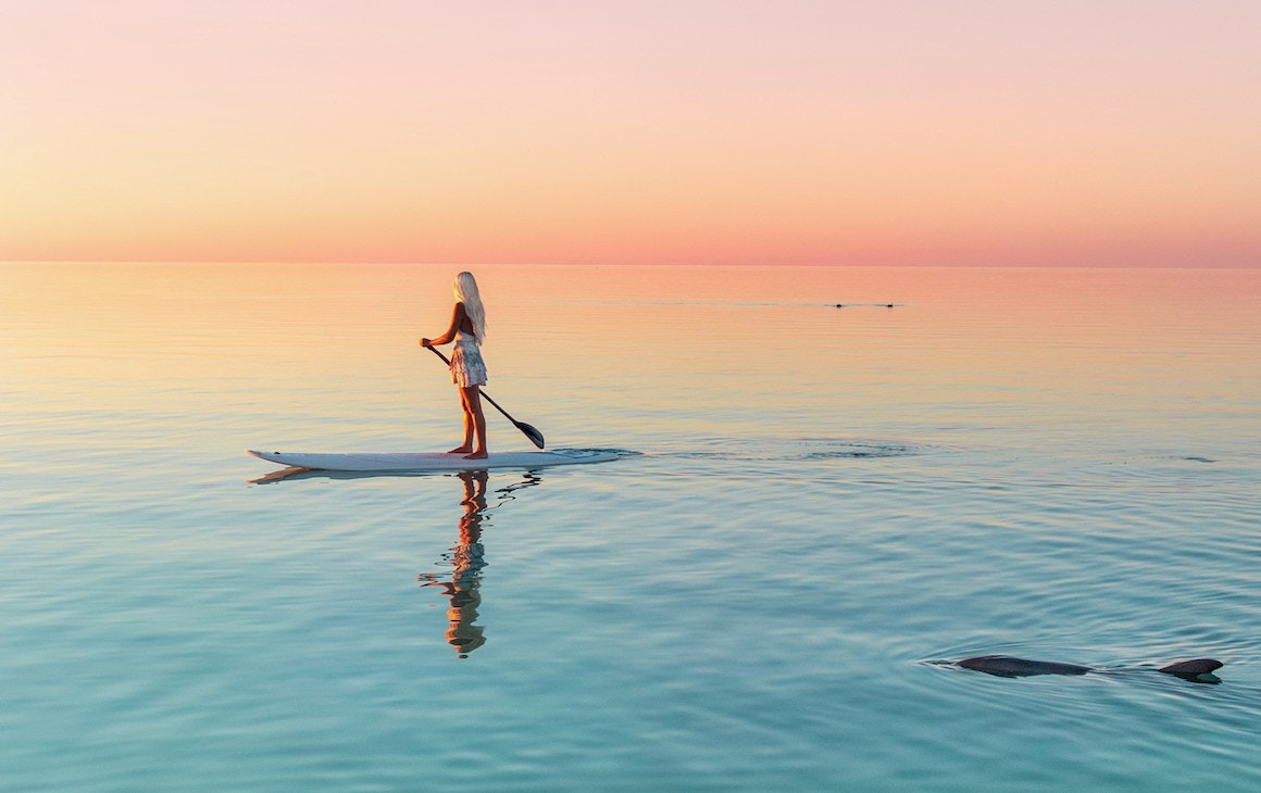 A stand up paddle boarder at sunset in Coral Bay