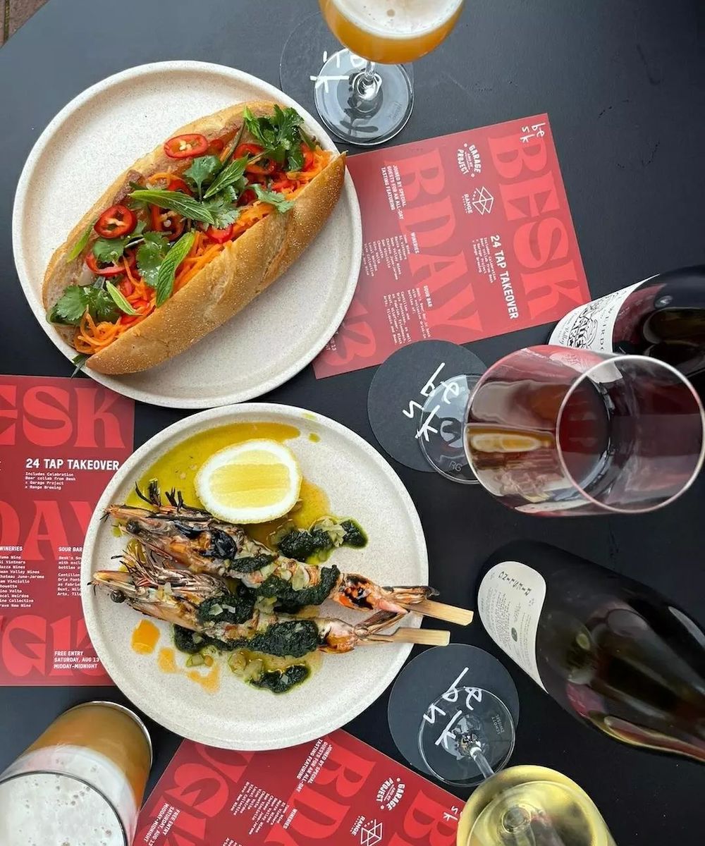 A table featuring a banh mi, grilled prawns and wine at Besk