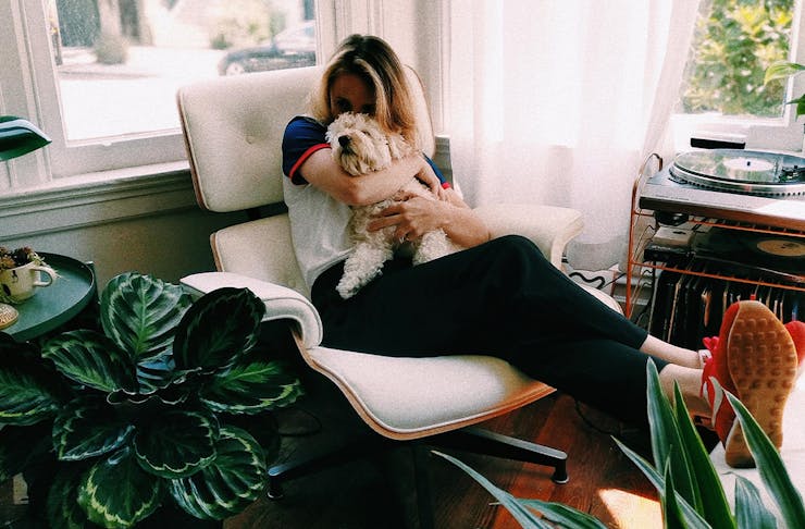 woman cuddling a puppy sitting on a lounge chair in her living room