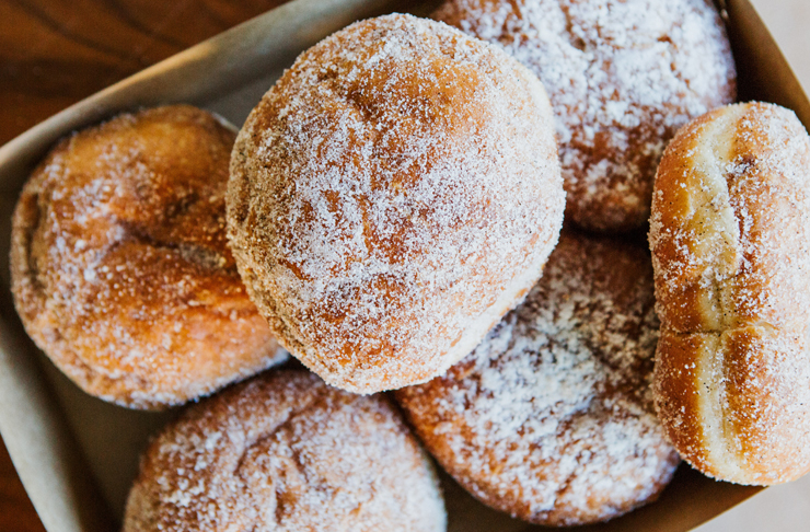 A takeaway box filled with cinnamon doughnuts.