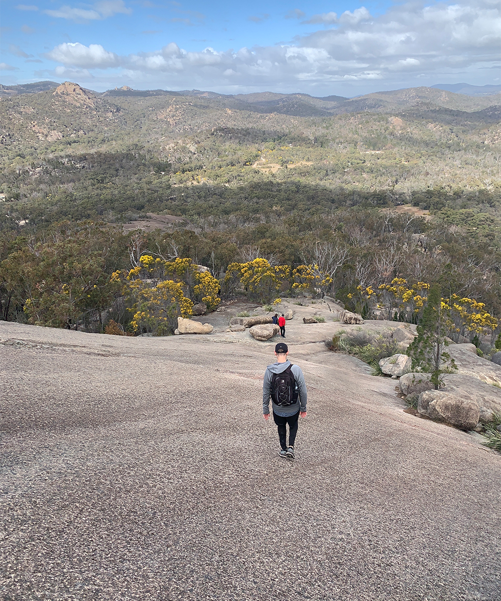 a person walking down a granite cliff face