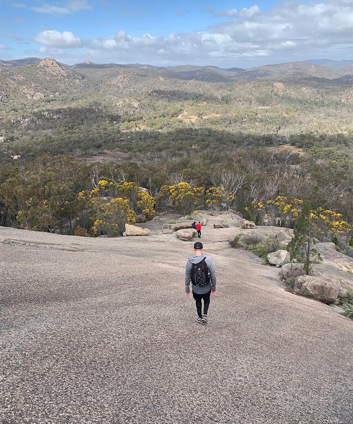 a person walking down a granite cliff face