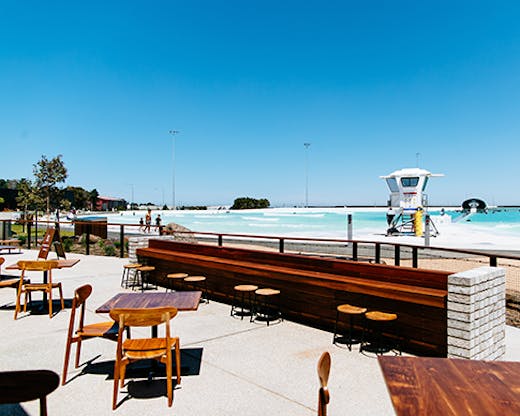 A restaurant next to a large surf park on a sunny day.