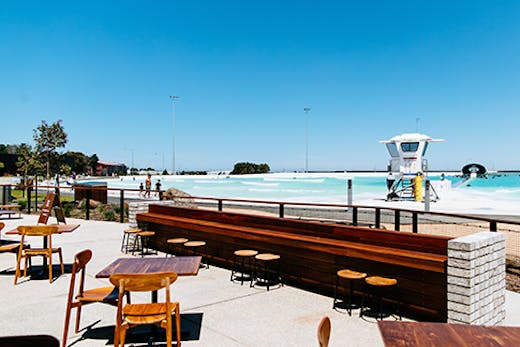 A restaurant next to a large surf park on a sunny day.