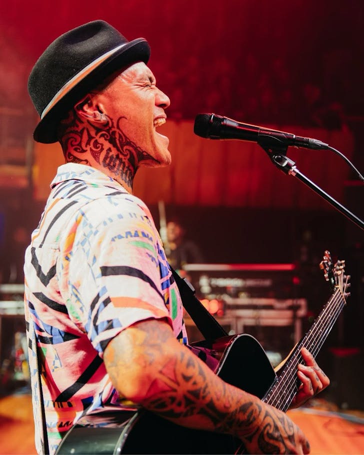 Tiki Taane beltin out a song live with his guitar in hand.