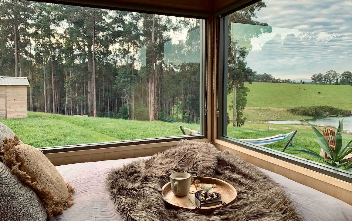 a bed with windows looking out to farm land