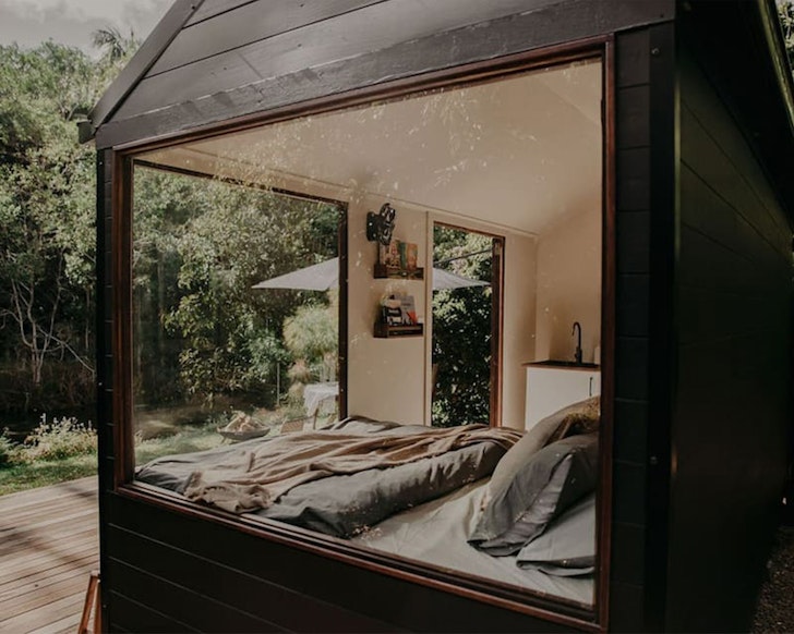 The bed at the lakehouse is seen through the window of the tiny home in South East Queensland