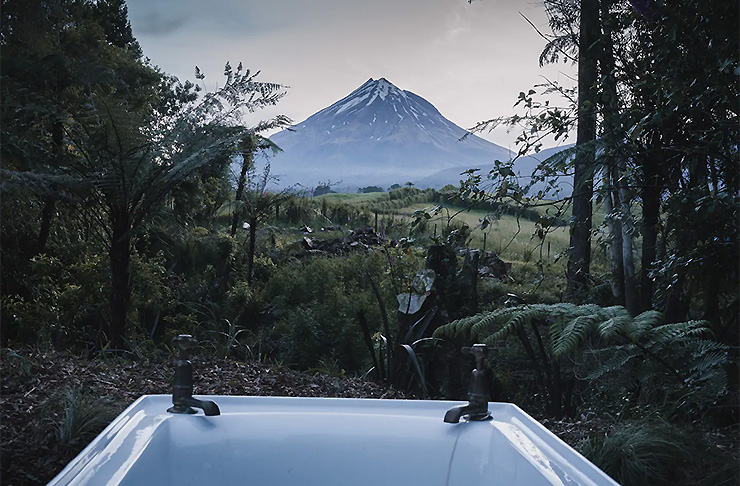A view from the tiny home accommodation showing a bath tub with Mount Taranaki in the background.