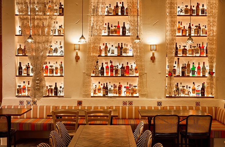 A warm, golden hued feature wall filled with bottles in one of the best Italian restaurants Melbourne has to offer. 
