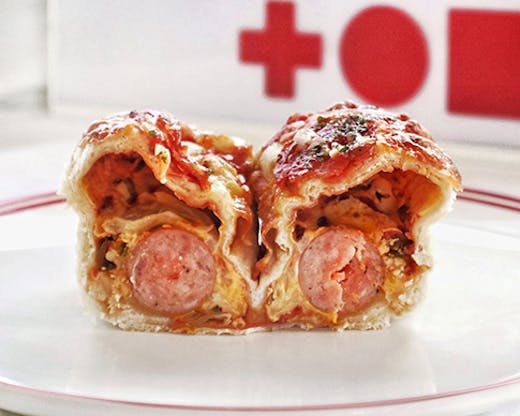 A loaf of pizza bread cut in half to reveal cheese, jalapeños, cheese and a whole sausage. 