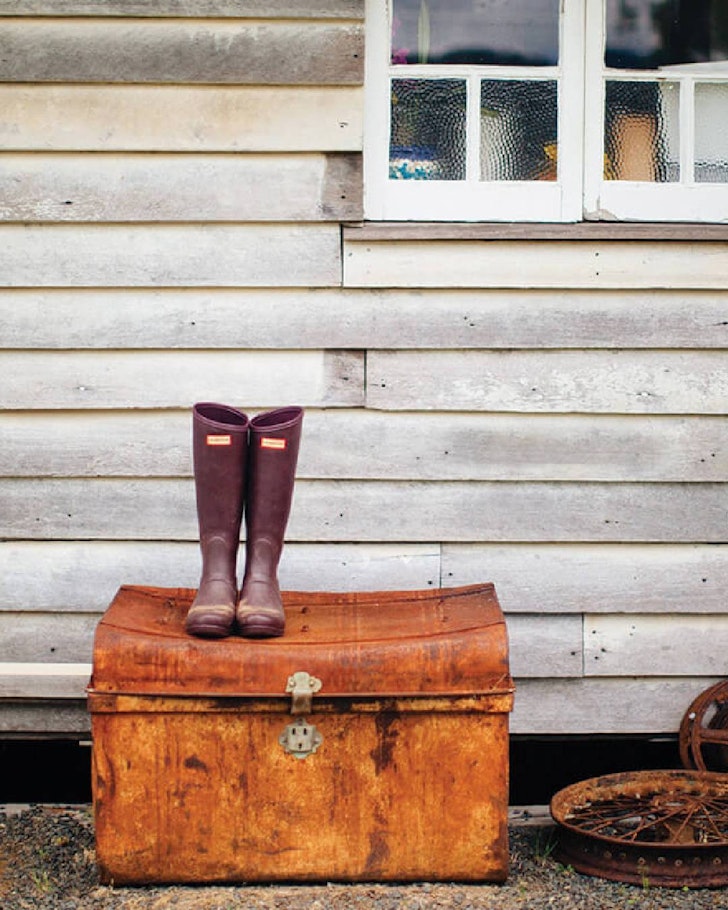 Wellington boots sit atop a vintage-looking chest at Tommerup’s Dairy Farm one of the best farm stays near Brisbane