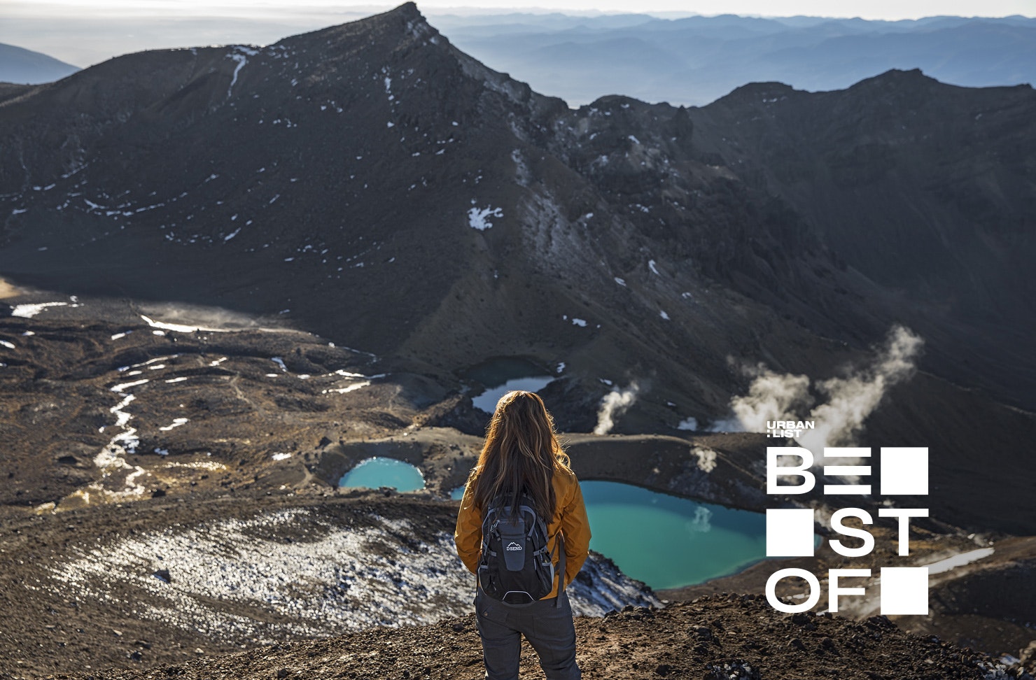 A walker looks out at a green lake on the Tongariro Crossing, Ruapehu