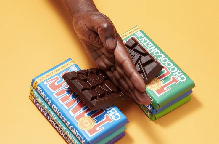 A hand slices a bar of Tony's chocolonely in half.