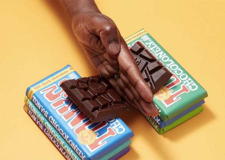 A hand slices a bar of Tony's chocolonely in half.