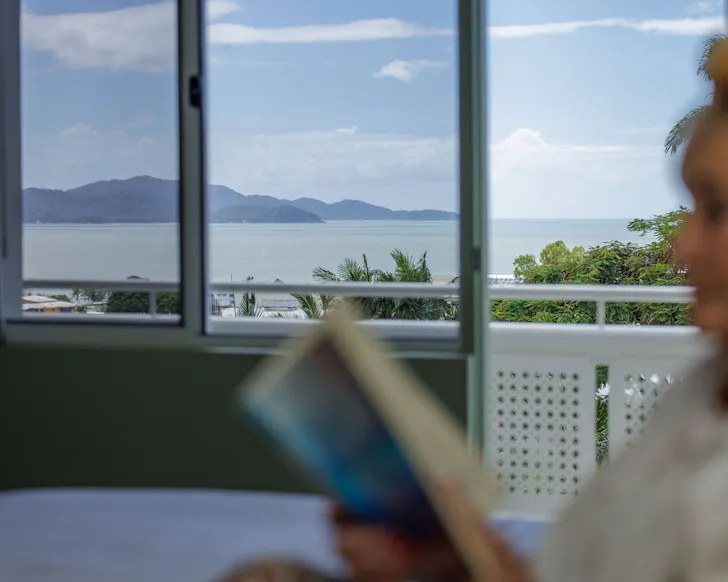 A guest reading inside with ocean views at victoria street boutique hotel townsville