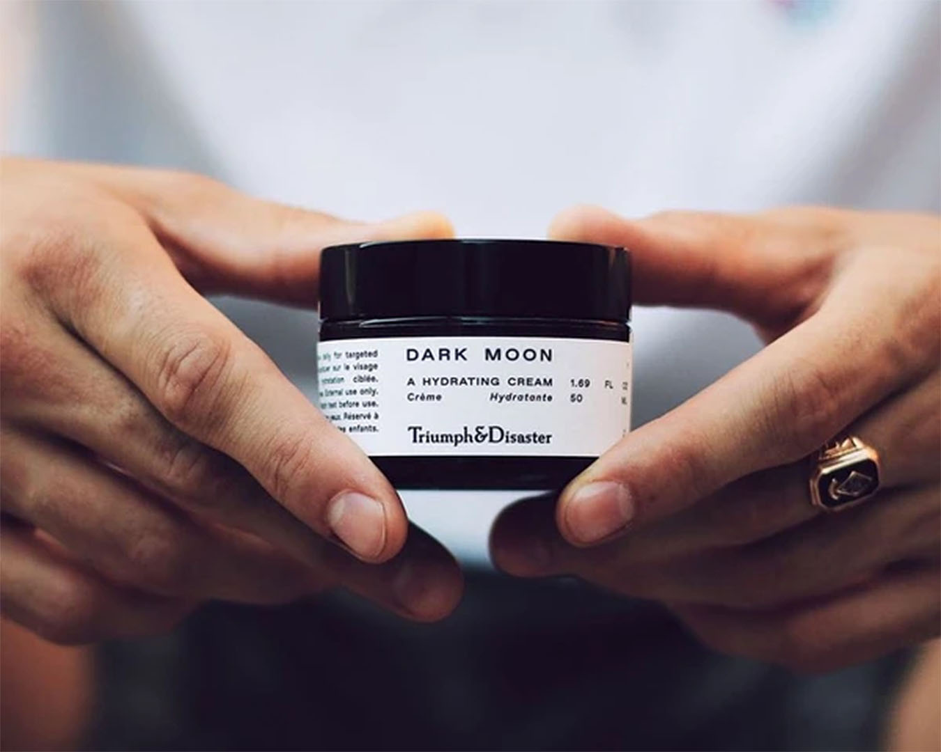 A man holds the Triumph & Disaster Dark Moon Hydrating Cream in his hands.