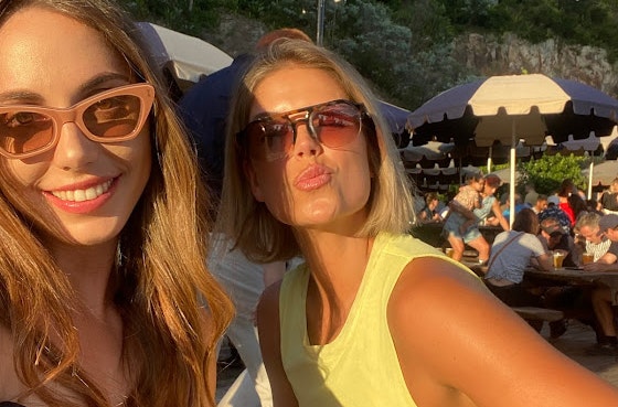 Two women smiling in the sun with sunglasses on