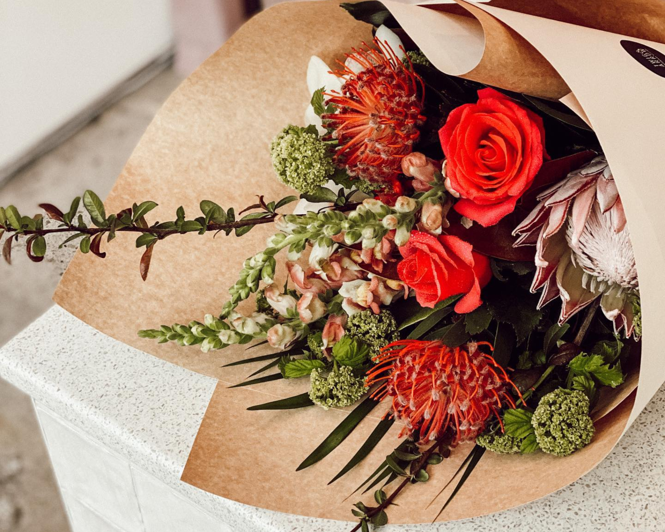 Flowers of red and pink are gorgeously arranged in this bouquet from Twig & Arrow
