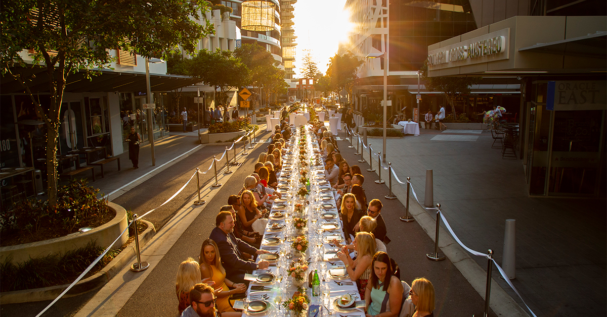 people sitting at a long dining table in the middle of broadbeach