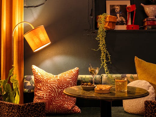 Plush cushions, hanging plants, and soft lamps surround a table at Uncanny bar in Newtown. 