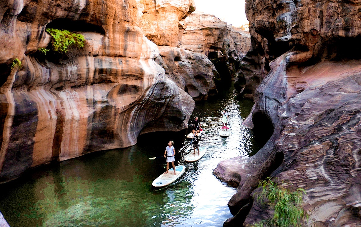 Several people SUP through a deep gorge