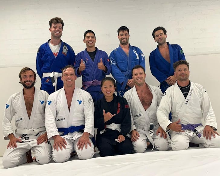 people in blue and white outfits smile for a photo at a sydney jiu jitsu studios