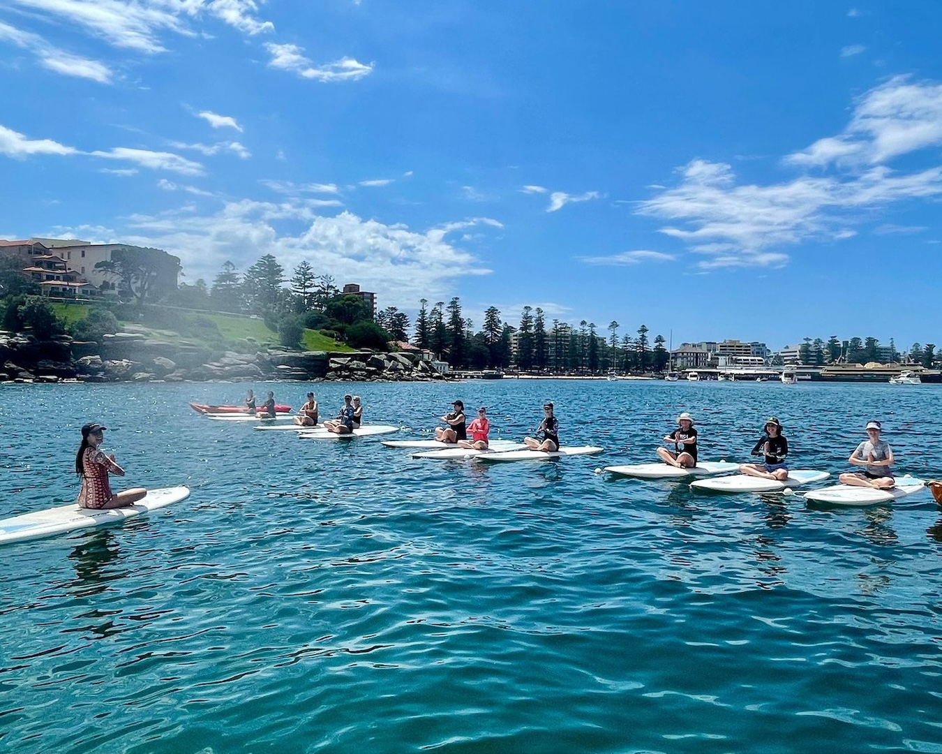 a line up of paddleboards on the water with people in a yoga position