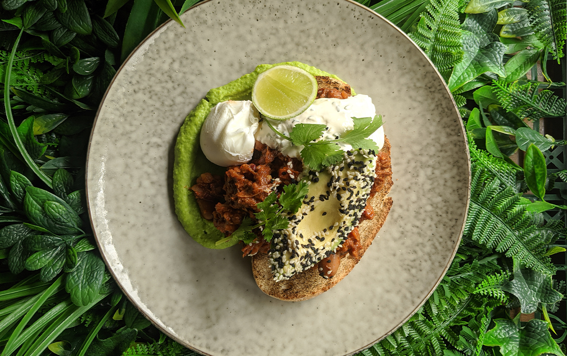 A plate of beans, avocado, brisket, poached eggs and toast