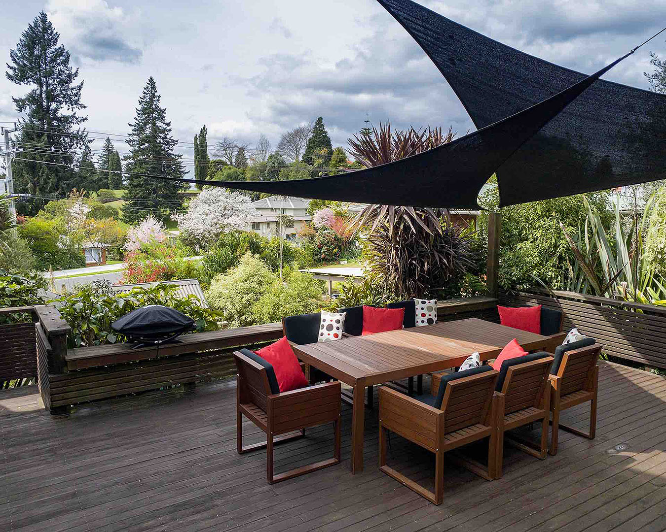 A wonderful looking deck with chairs and a table overlooks lots of trees at this airbnb in central Rotorua.