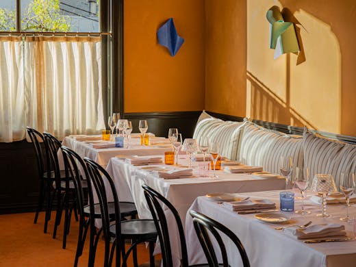 The dining room at Ursula's Paddington, with caramel coloured walls, and tables with white table cloths. 